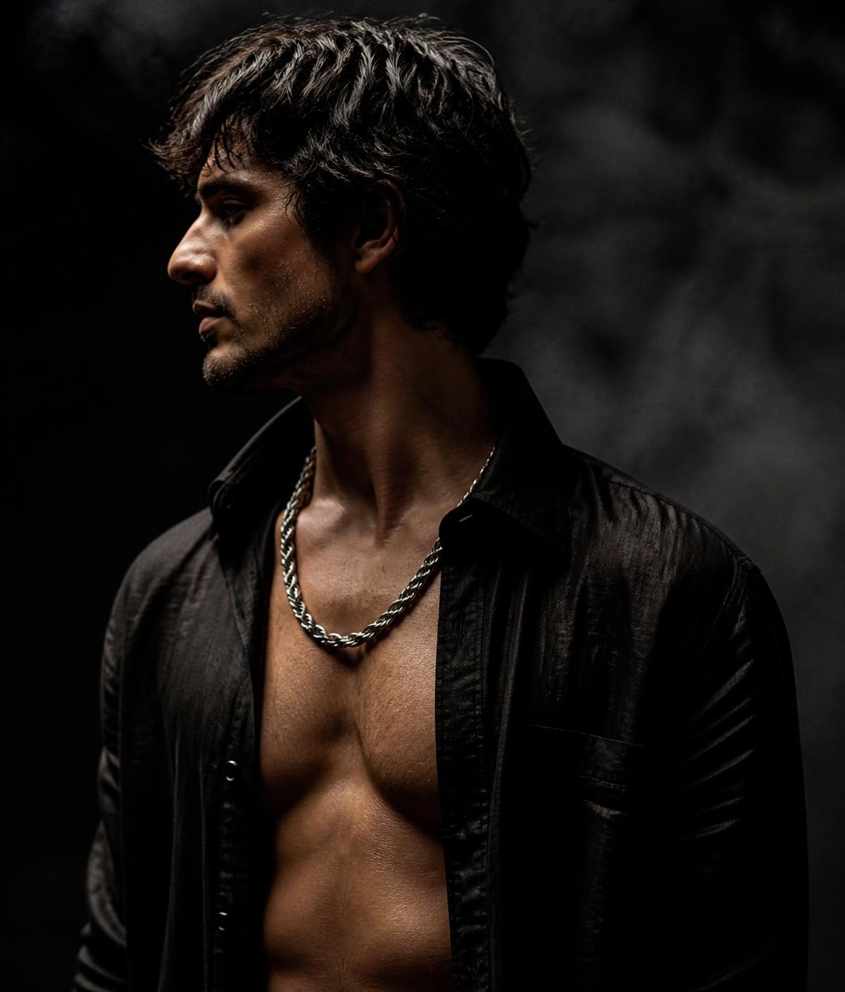 Man in an open black linen shirt wearing a heavy silver rope chain
